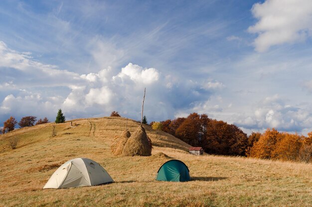 Acampar com duas tendas turísticas nas montanhas. Paisagem de outono