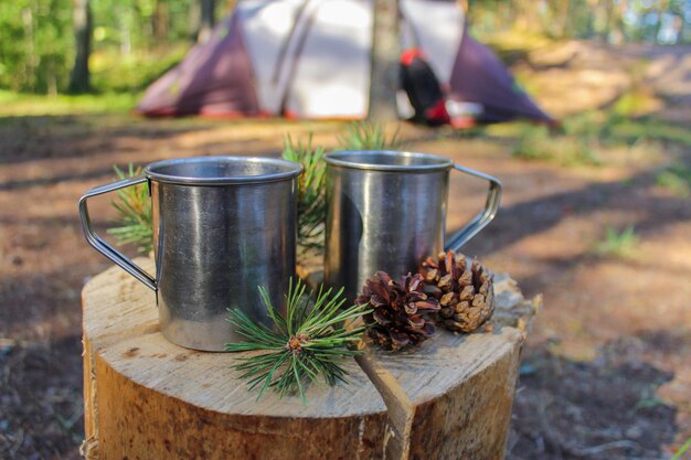 Foto acampar en la naturaleza tazas de hierro turísticas en el bosque con té de hierbas cocinado en un fuego