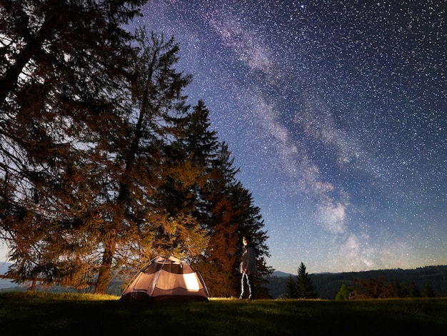 Acampar de noche en las montañas bajo el cielo estrellado y la vía láctea.