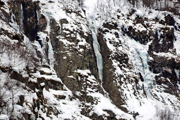 Acantilado escarpado cubierto de nieve y grandes carámbanos