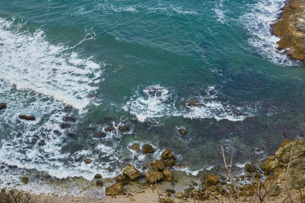 Acantilado rocoso junto al mar con olas blancas.