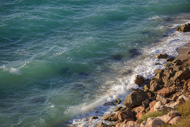 Acantilado rocoso y perezosas olas turquesas