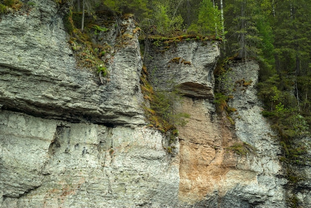 Acantilados rocosos de piedra caliza arbolada con una figura que se asemeja a una cara fea