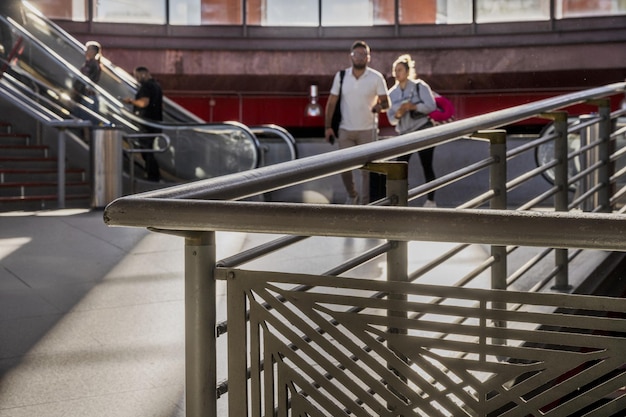 Acceso entre barandillas y personas a las estaciones de metro y tren desde las escaleras mecánicas