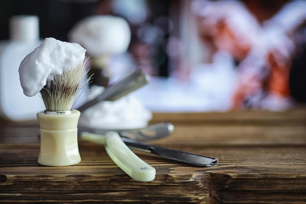 Accesorios de afeitado sobre un fondo de textura de madera. Instrumentos. Máquina de afeitar, cepillo, espuma y maquinilla de afeitar desechables.