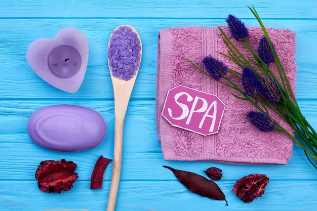 Accesorios aromáticos de baño spa laicos planos en madera azul. Jabón con sal marina, flores y pétalos.