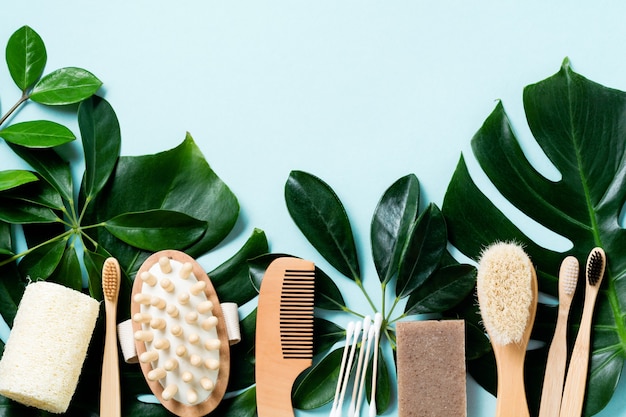 Accesorios de baño ecológicos o herramientas de spa en hojas monstera sobre fondo azul. Fondo de hormigón cosmético. Concepto de belleza y desperdicio cero.