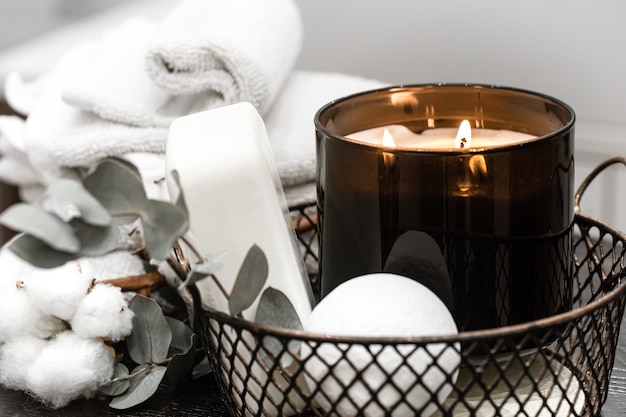 Accesorios de baño y una vela encendida en una canasta. Concepto de aromaterapia.