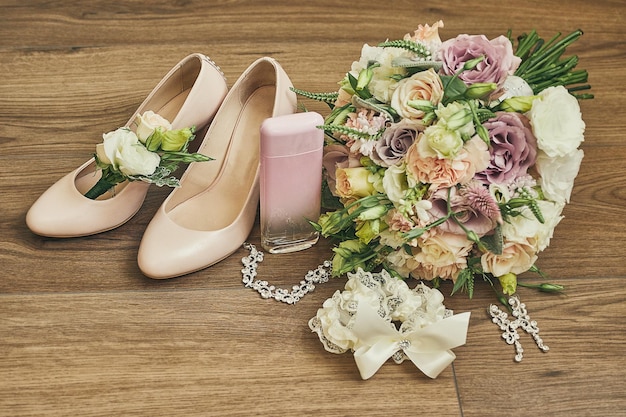 Accesorios de boda de la novia, como zapatos de tacón alto, pendientes de ramo, collar, perfume y liga.