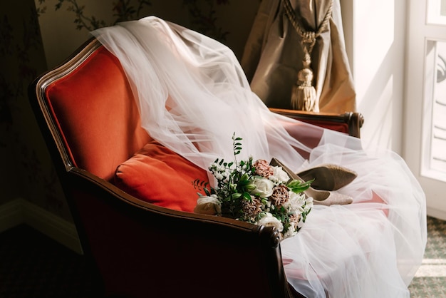 Accesorios de boda de los zapatos de ramo de novia velo en una silla roja