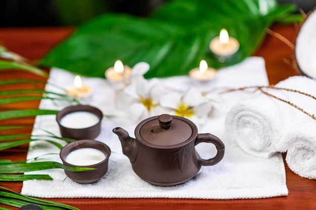 Accesorios para la ceremonia del té ubicados en una toalla blanca con velas y flores blancas