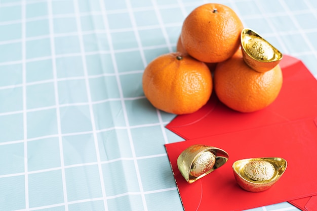 Accesorios en concepto de vacaciones de año nuevo lunar y año nuevo chino. Naranja en plato blanco con dinero rojo