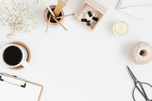 Accesorios de espacio de trabajo café y una gypsophila en un jarrón sobre una mesa blanca Plano con espacio de copia en blanco