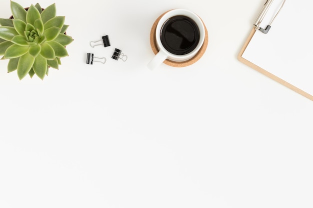 Accesorios de espacio de trabajo café y una planta suculenta en una mesa blanca Plano con espacio de copia en blanco