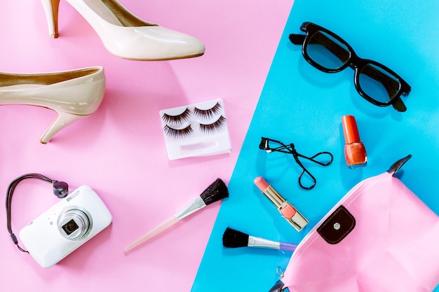 Accesorios femeninos y zapatos con cosméticos en fondo rosa