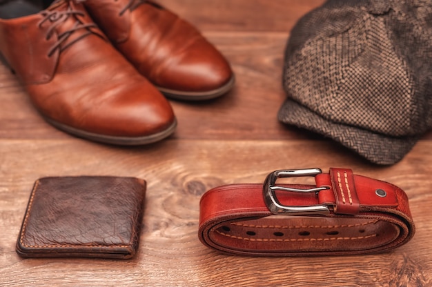 Accesorios para hombre zapatos de cuero marrón billetera gorro de lana y cinturón de cuero sobre un fondo de madera