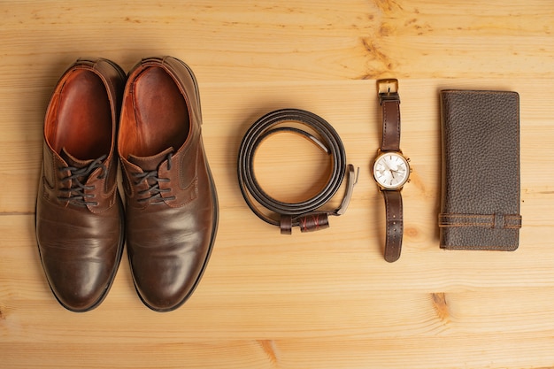 Accesorios para hombres con billetera de cuero marrón, cinturón, zapatos y reloj en superficie de madera