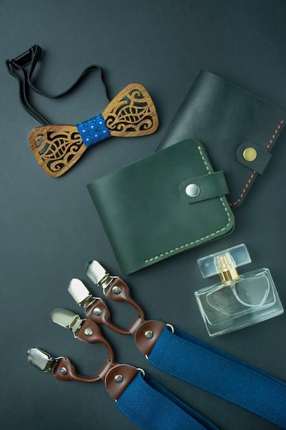 Accesorios para hombres. Cartera de hombre, mariposa de hombre, tirantes y perfume sobre fondo oscuro. Kit de hombre. Espacio para texto. Copia espacio