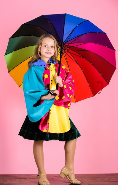 Los accesorios impermeables hacen que los días de lluvia sean alegres y agradables. Confiada en sus prendas de otoño. Fabricación de accesorios impermeables. Kid girl happy hold colorido paraguas use capa impermeable.