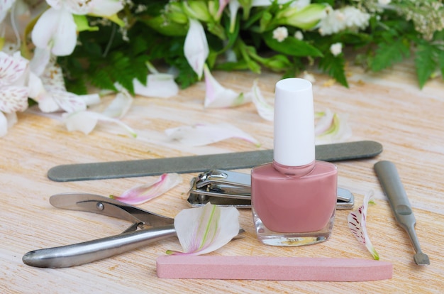 Accesorios de manicura: esmalte de uñas desnudo, lima de uñas de diamante, quita cutículas, cortaúñas y empujador de uñas. Concepto de manicura en casa.