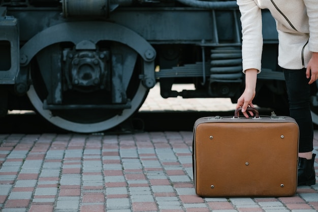 Accesorios de moda de viaje. estilo maleta retro vintage hipster. destino del viaje de transporte. mujer en una estación de tren. concepto de espacio libre