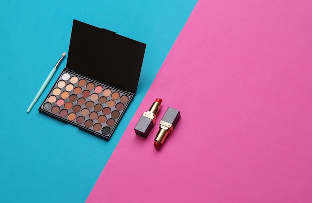 Accesorios para mujeres Productos de belleza sobre fondo rosa azul Maquillaje paleta de sombra de ojos pinceles de maquillaje y lápiz labial Diseño creativo