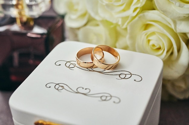 Los accesorios de la novia, como los zapatos, el bouquet, el anillo y el perfume, se encuentran en una mesa.