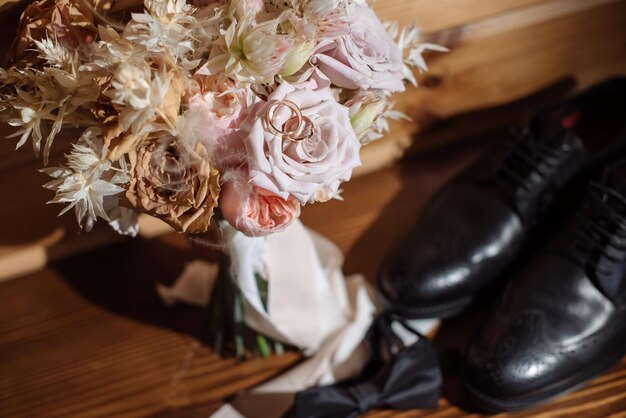 Accesorios de novios para anillos de boda zapatos corbatín y ramos de flores en la mañana