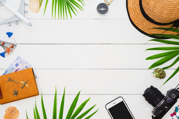 Accesorios planos del viajero de la endecha en el fondo de madera blanco. Concepto de viajes y vacaciones de horario de verano.