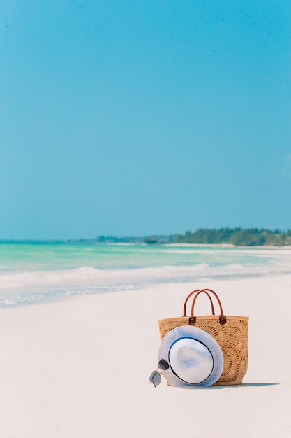 Accesorios de playa: bolso de paja, sombrero y anteojos en la playa