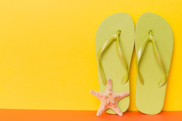 Accesorios de playa Chanclas y estrellas de mar sobre fondo de color Mock up con espacio de copia