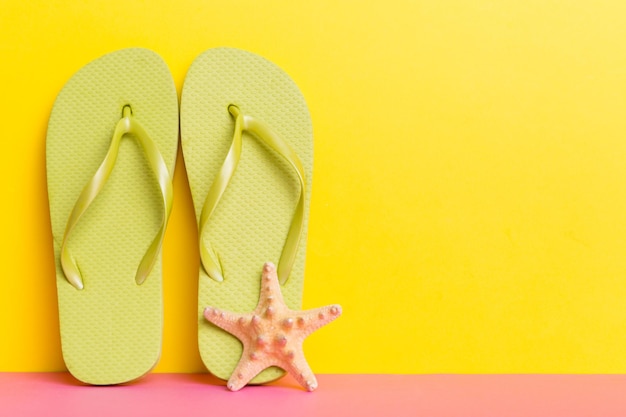 Accesorios de playa Chanclas y estrellas de mar sobre fondo de color Mock up con espacio de copia