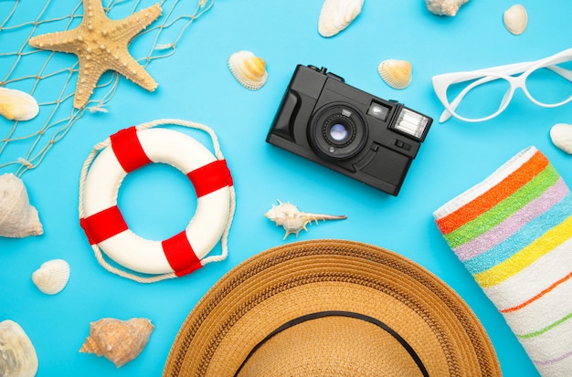 Foto accesorios de playa con hojas de palma sobre fondo azul.