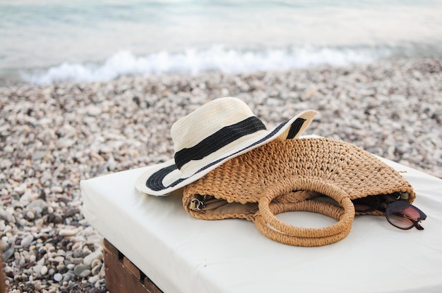 Accesorios para la playa planas, sombrero de paja, bolsa de verano y gafas de sol en la tumbona.