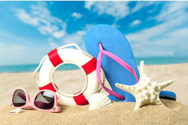 Accesorios de playa sobre arena. Chanclas, gafas de sol, estrella de mar