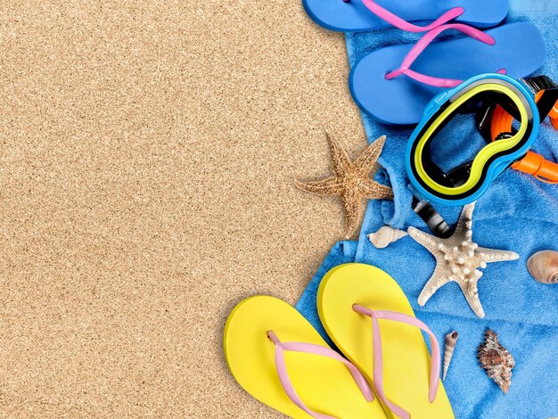 Foto accesorios de playa sobre arena. chanclas, gafas de sol, estrellas de mar, toalla