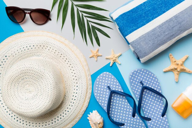 Accesorios de playa sombrero de paja y conchas marinas en mesa de colores Fondo de concepto de verano