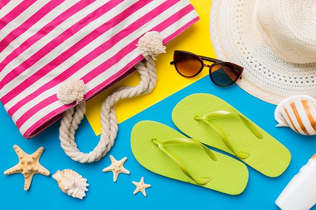 Accesorios de playa sombrero de paja y conchas marinas en mesa de colores Fondo de concepto de verano