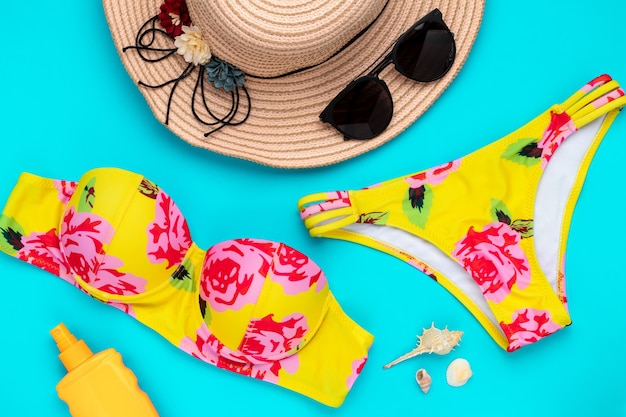 Accesorios de playa de verano sobre un fondo azul. ropa de playa de moda, bikini amarillo. el de marina, ocio. bañador estampado floral. traje de baño para mujer. | Foto