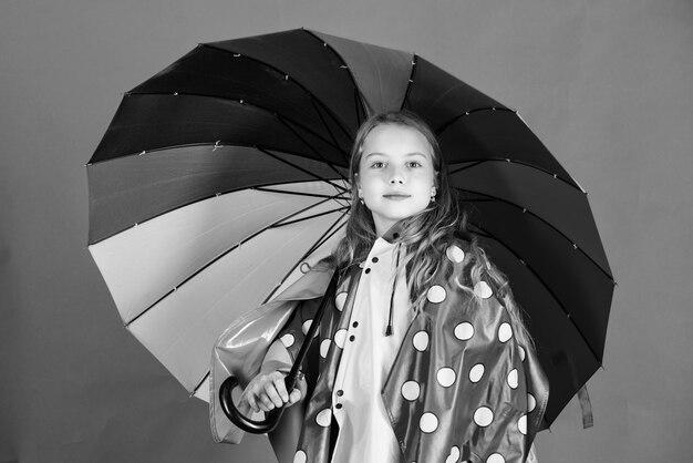 Los accesorios a prueba de agua hacen que los días de lluvia sean alegres y placenteros Los niños y las niñas felices sostienen un colorido paraguas y usan una capa impermeable Disfruta del clima lluvioso con la ropa adecuada Fabricación de accesorios a prueba de agua