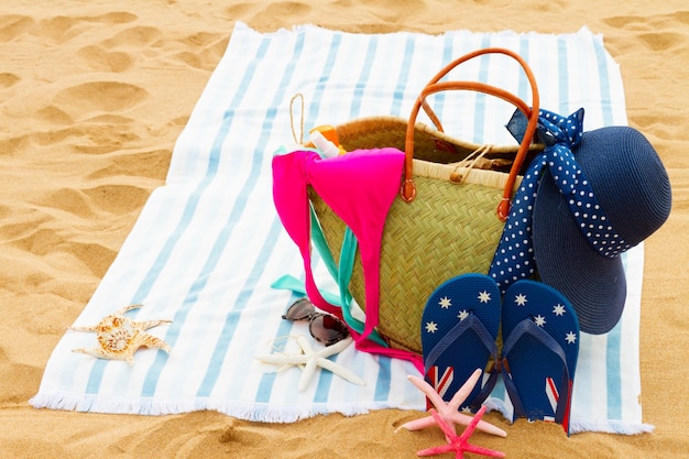 Accesorios para tomar el sol en una gran bolsa de paja en la playa de cerca