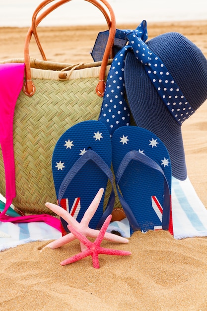 Accesorios para tomar el sol con sombrero en bolsa de paja en la playa de arena junto al mar