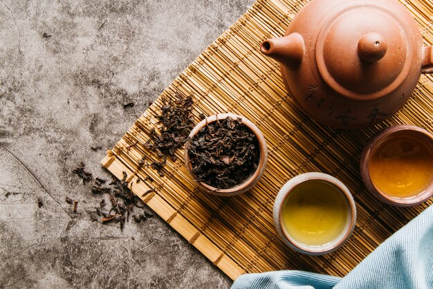 Accesorios tradicionales para la ceremonia del té con tetera y taza de té en mantel individual