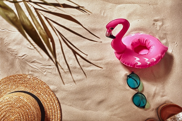 Los accesorios para las vacaciones de los viajeros se colocan en una vista superior plana de arena de playa blanca