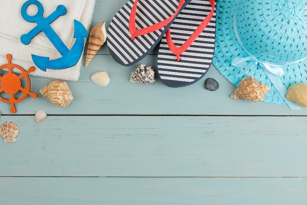 Accesorios de verano. accesorios de playa. azotes, sombrero, conchas y toalla sobre una mesa de madera azul. vista superior.