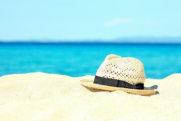 Accesorios de verano: sombrero en la arena a la orilla del mar.