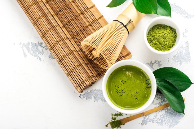 Accesorios verdes de la bebida y del té del té del matcha en el fondo blanco