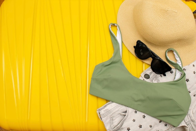 accesorios de viajesombrero de veranogafas de soltraje de baño en maleta amarilla planificación viaje vacaciones