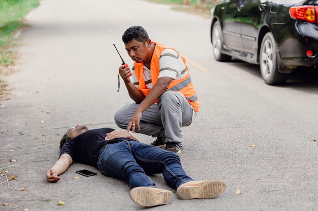 Accidente de hombre se acostó inconsciente en la carretera atropellada por un automóvil mientras tocaba la radio del personal del equipo de emergencia del teléfono para pedir ayuda