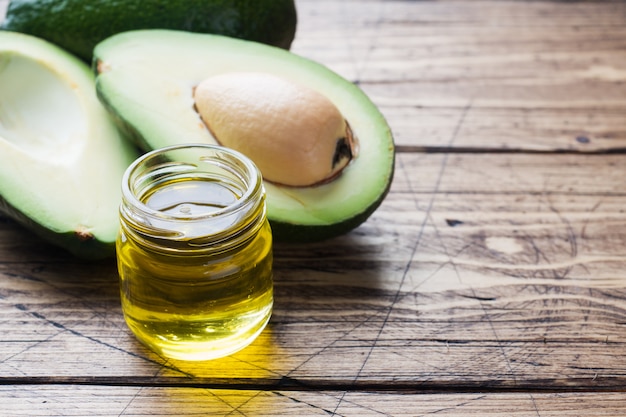 Aceite del aguacate y del aguacate en el fondo de madera con el espacio de la copia.